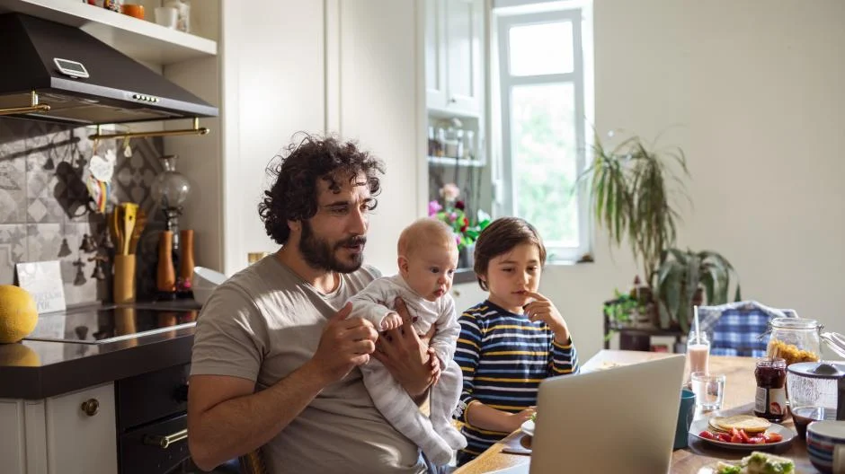 Close up of a single father using a laptop and having breakfast with his kids Co-ouderschap en werk Ik ben de vader